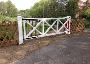 View of the level crossing gates marking the start of the Marriott's Way route at Barn Road.