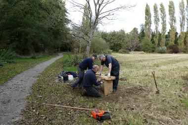 Photograph of 3 workers constructing a wooden bench next to the path through Cringleford Meadow. (Photo by Robert Stubbs)