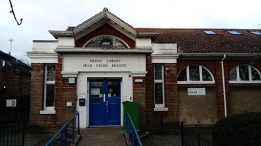 Exterior photograph of Mile Cross Library showing the ramp to the entrance and bike racks on the library wall.