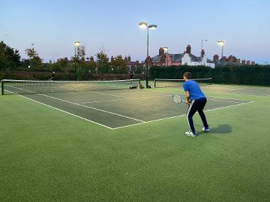 A man preparing to receive a serve on a tennis court.