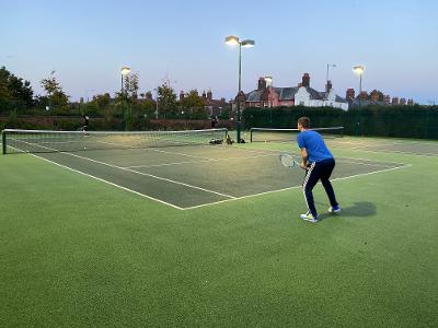 A man preparing to receive a serve on a tennis court.