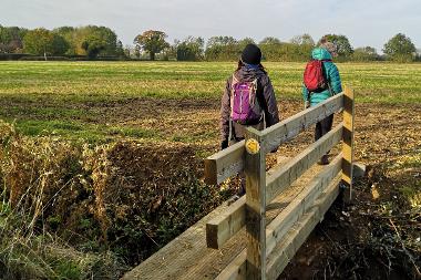 Two people walking over a bridge on the Kett's Country Trail.