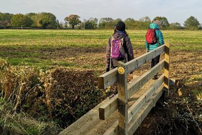 Two people walking over a bridge on the Kett's Country Trail.