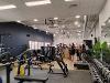 The image shows the inside of Aylsham Gym & Fitness Hub, with various pieces of sports equipment and people talking in the background.